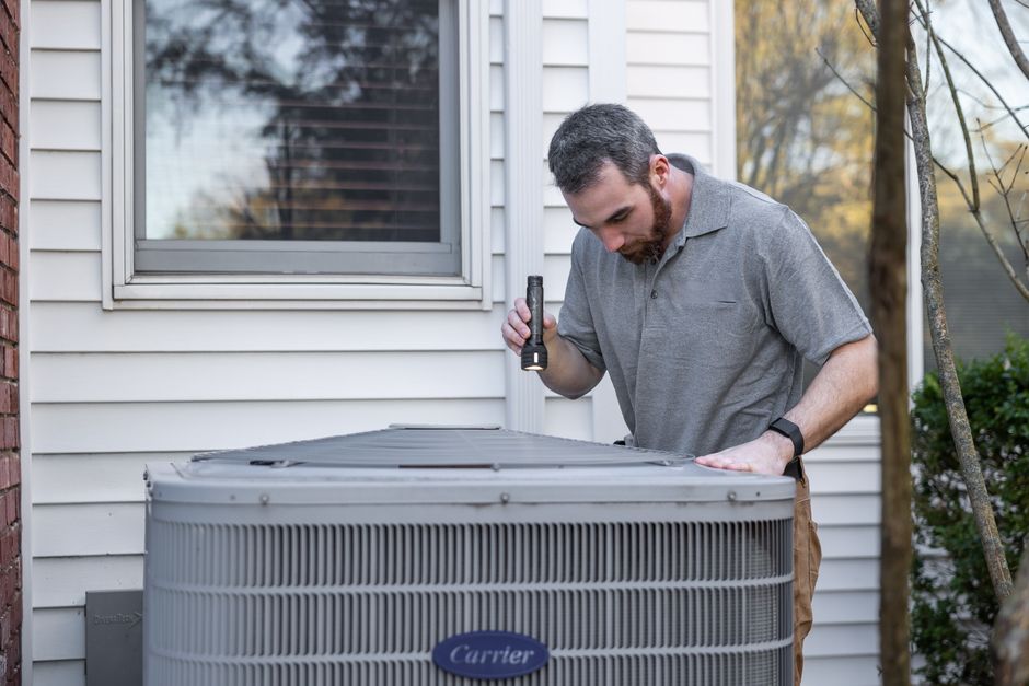 Technician conducting a professional inspection of an outdoor HVAC condenser unit