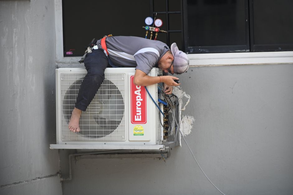 HVAC technician repairing an outdoor air conditioning unit