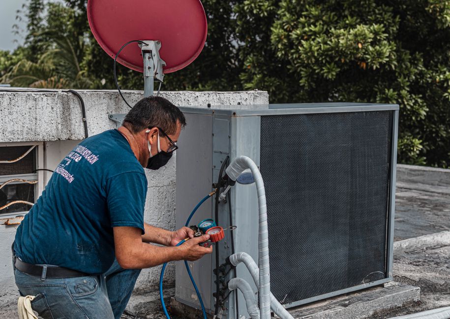 Technician servicing an air conditioner with a manifold gauge